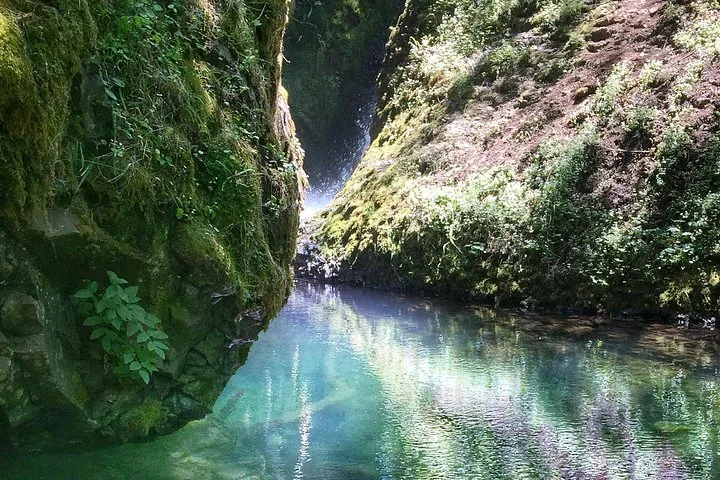 Piscina d'acqua blu cristallina ai piedi di una cascata rocciosa