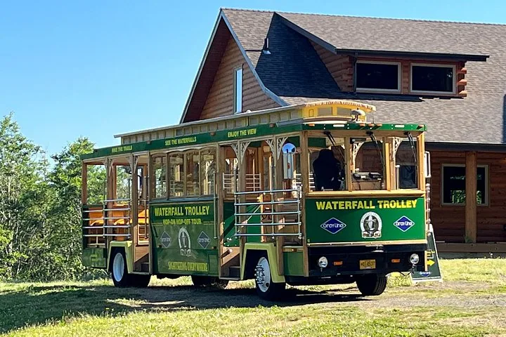 Il Waterfall Trolley parcheggiato accanto a un rustico edificio in tronchi